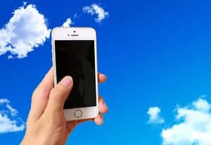 スマートフォンを持つ手の背景に空を合成した画像